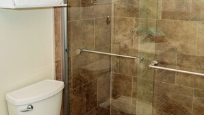Ein Badezimmer mit einer Duschkabine, einer Toilette und einem Ablagefach mit gefalteten Handtüchern.