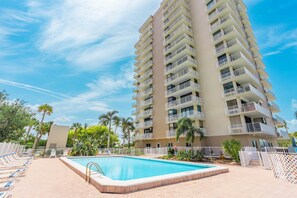 A high-rise hotel with a swimming pool, multiple balconies, and a clear sky. - #306 Lovers Key Beach Club (Bonita Springs)