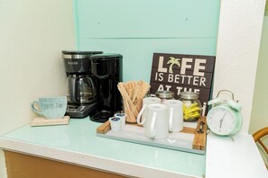 A coffee station with a coffee maker, mugs, and a sign that reads "Life is better at the jar."