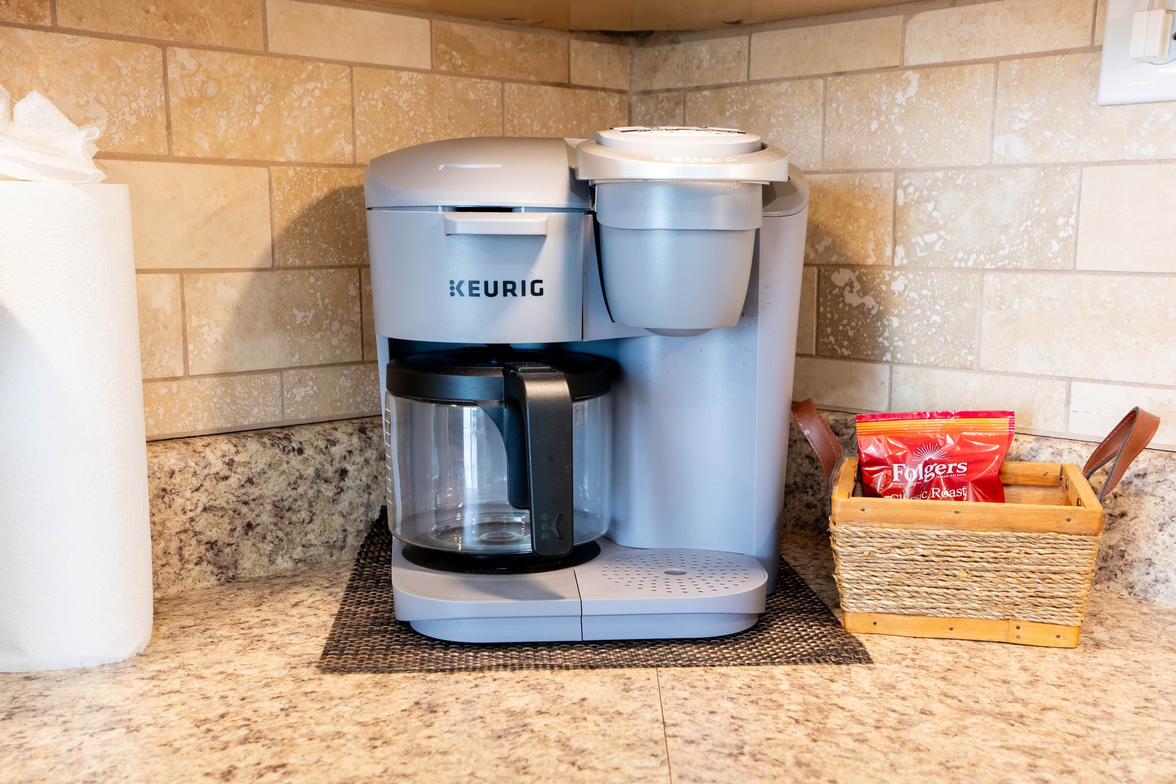 A Keurig coffee maker on a kitchen counter with a coffee pod box and a paper towel dispenser.