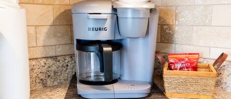 A Keurig coffee maker on a kitchen counter with a coffee pod box and a paper towel dispenser.