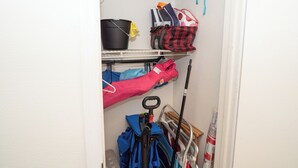 A storage area with shelves containing bags, a mop, and cleaning supplies. - #803 Lovers Key Beach Club Ocean Views (Bonita Springs)