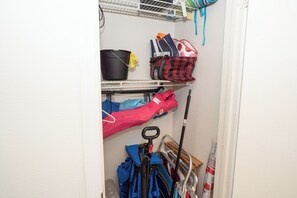 Un espace de rangement avec des étagères contenant des sacs, une serpillière et du matériel de nettoyage.
