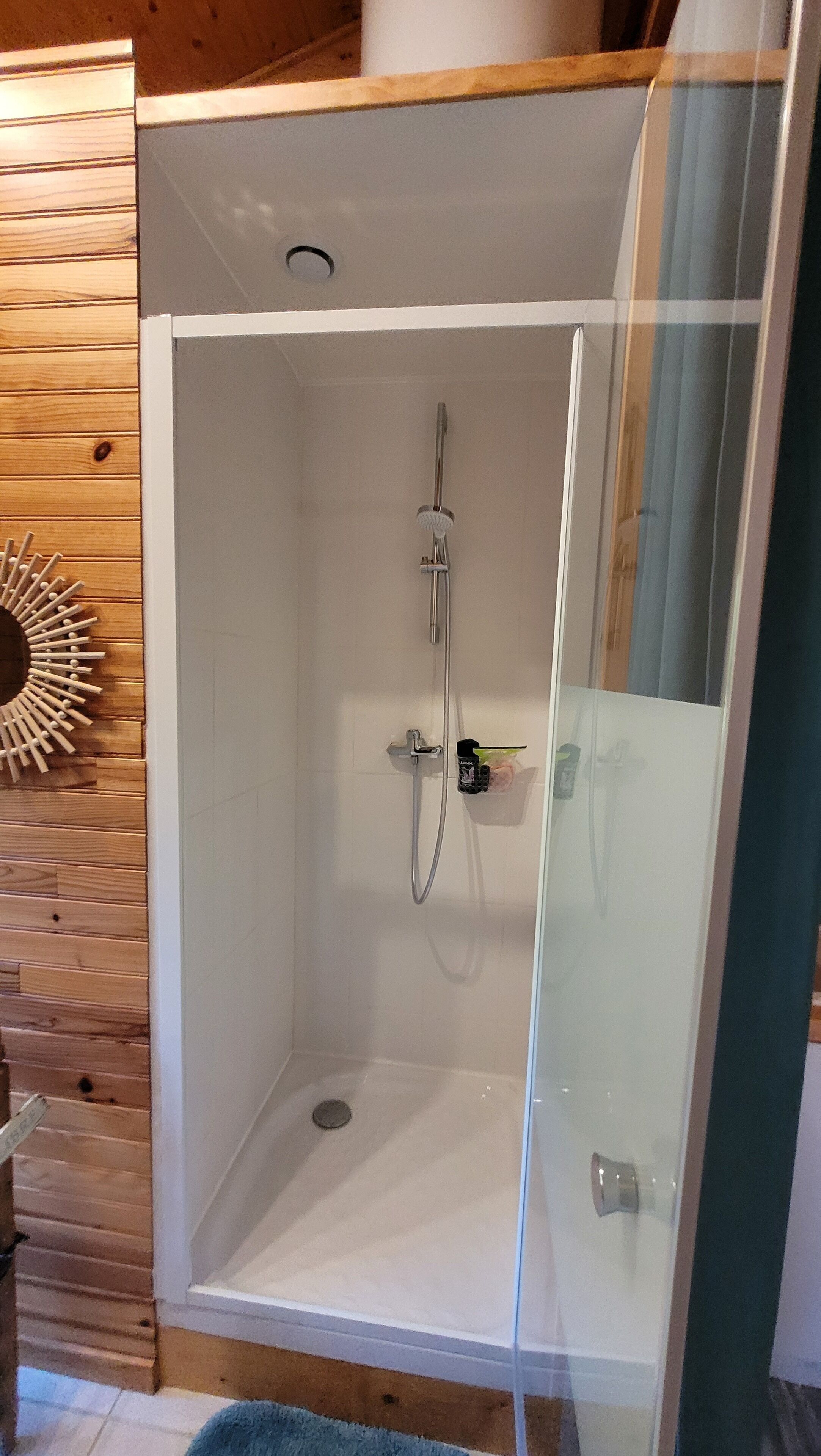 Een douchecabine met glazen wanden, voorzien van een handdouche.