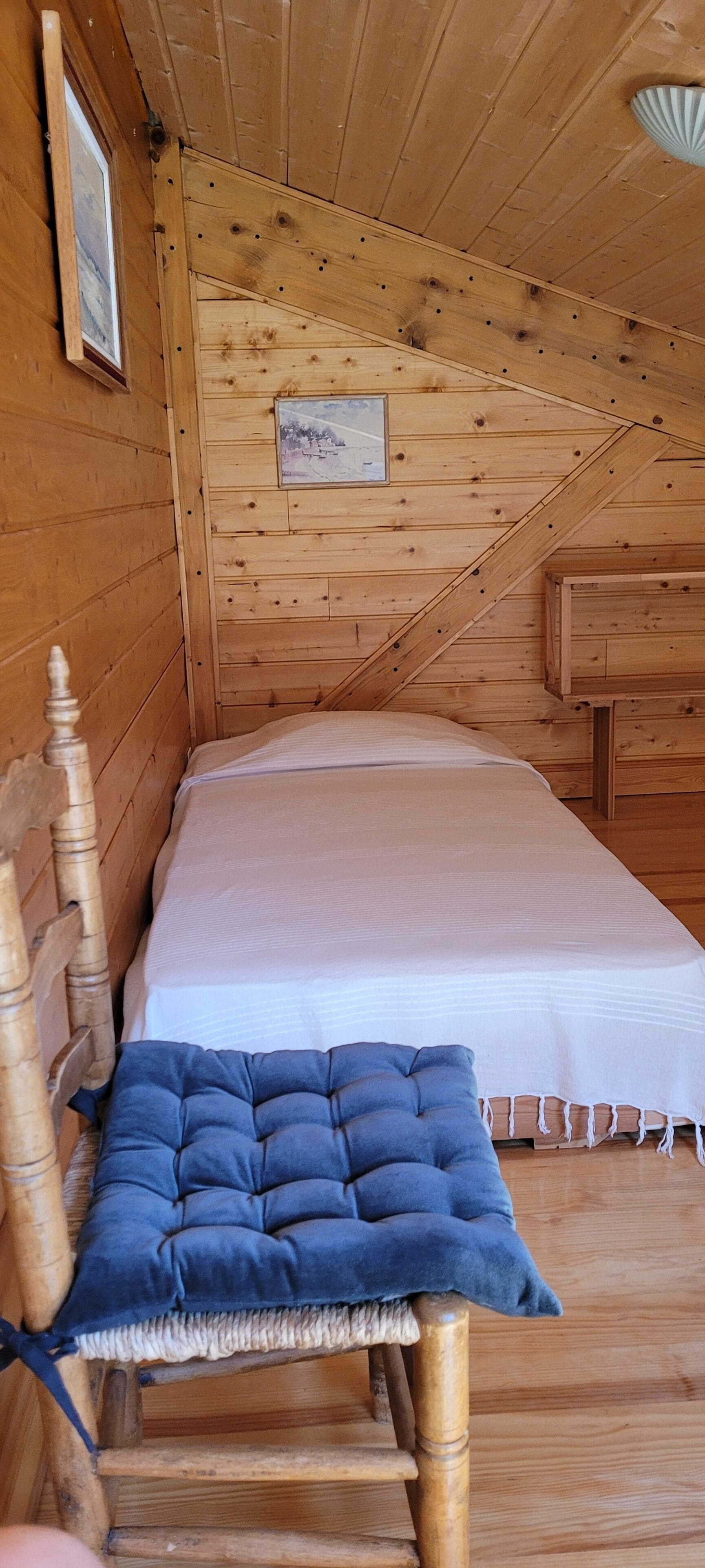 Een houten kamer met een bed, een stoel en een kleine tafel.