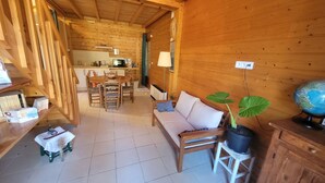 A wooden cabin interior with a dining area, a sofa, a globe, and a potted plant. - Reflet de Bien être : Wooden loft for 3 people with enclosed courtyard. (Marsoulas)