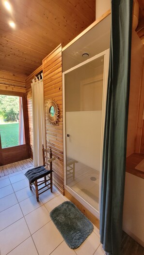 A wooden cabin interior with a shower, a bench, and a view of the outdoors. - Wooden loft for 3 people. (Marsoulas)