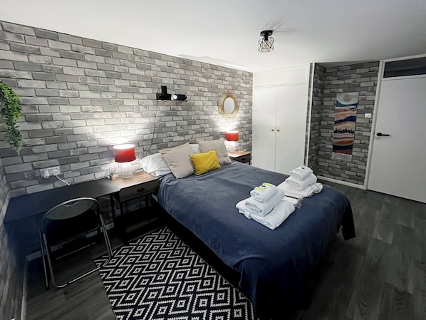 Cozy retreat with a brick-patterned accent wall, a comfortable bed, and a stylish wardrobe.