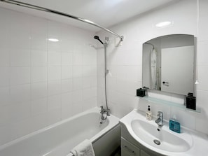 Bathroom features a bathtub, glass shower enclosure, and a sink with chrome fixtures.