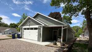 A two-story building with a garage, a covered porch, and a gravel driveway.