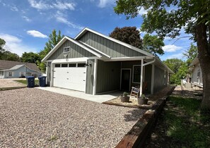 Ein zweistöckiges Gebäude mit Garage, überdachter Veranda und einem Schotterweg.