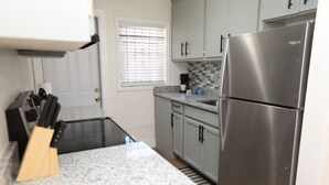 Eine Küche mit Edelstahl-Kühlschrank, Granit-Arbeitsplatten und einem schwarzen Herd.