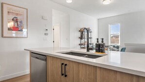 A modern kitchen with a dishwasher, a sink, and a built-in wine cooler. - King Bed » Garage » AC » Full Kitchen » 65` (Calgary)