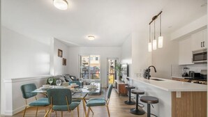 A modern kitchen with white cabinets, a central island, and pendant lighting. - King Bed » Garage » AC » Full Kitchen » 65` (Calgary)
