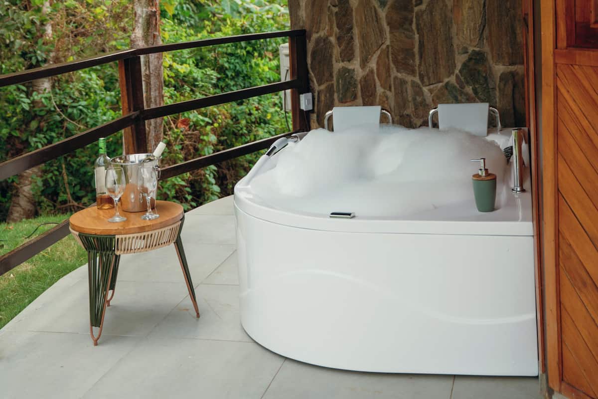 A spa area with a stone wall, a thatched roof, and a hot tub.