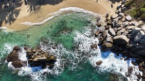 Une plage avec de l’eau claire, des rochers et des gens.