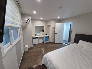 Une chambre d’hôtel moderne équipée d’un lit, d’un bureau, d’un miroir et d’une fenêtre avec des stores.