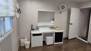 A compact bedroom with a bed, a desk, a small cabinet, a fan, and a door. - U-Rim Stay (Seoul)