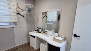 A modern bathroom with a white vanity, a mirror, a fan, and a door. - U-Rim Stay (Seoul)