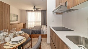 A compact kitchen with a dining area, a ceiling fan, and a bed with curtains. - King Studio w/ Private Balcony + Rooftop Pool, Gym (Tulum)