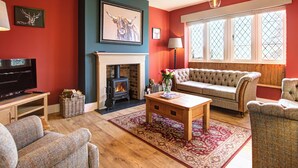 A cozy living room with a fireplace, a sofa, a television, and a wooden coffee table.