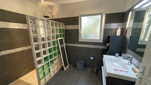 Une salle de bain moderne avec une douche, une fenêtre, un lavabo et un miroir.