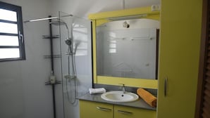 A bathroom with a glass shower enclosure, a sink with a mirror above it, and a towel on the counter. - Villa Horizon Caraïbes (Petit-Bourg)