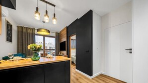 Une cuisine moderne avec un plan de travail en bois, des meubles de couleur noire et des luminaires suspendus.