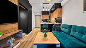 Un salon moderne avec une table basse en bois, un canapé de couleur turquoise et un téléviseur posé sur un meuble en bois.