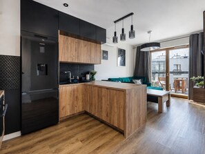 A modern kitchen with a central island, black appliances, and a dining area with a table and chairs.