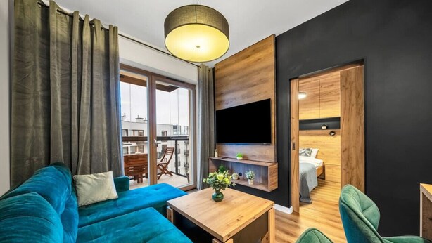 Un salon moderne avec un canapé bleu, une table basse en bois et un téléviseur fixé au mur.
