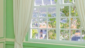 A room with a large window, green walls, and a bed.