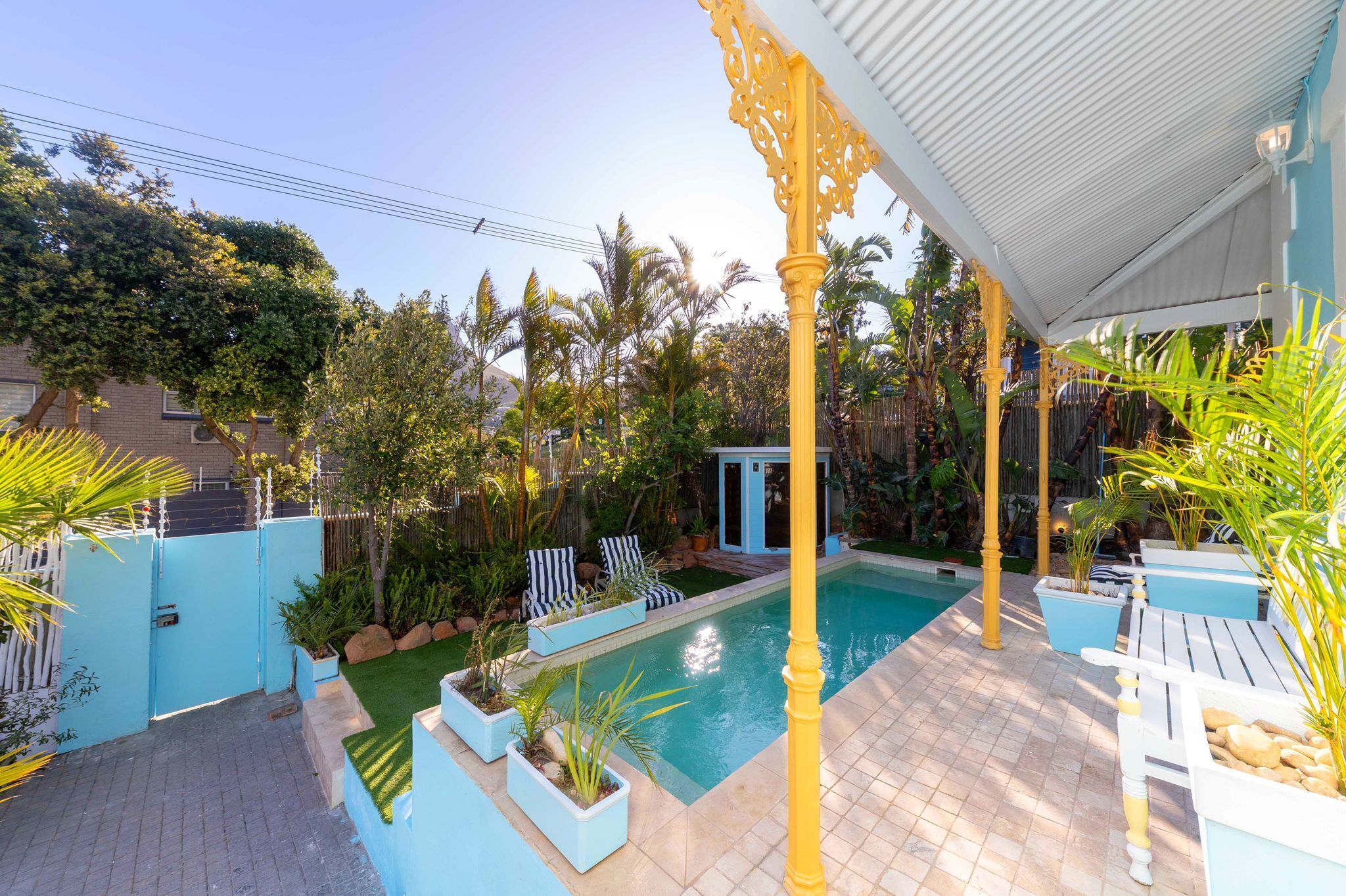 Un espace piscine doté d’une terrasse carrelée, de chaises longues et d’un coin salon abrité.