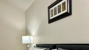 A neatly made bed with grey bedding, a dark headboard, and a framed picture above it. - Cozy Home in Spring,TX with AC /WiFi / Laundry . 20 mins from IAH Airport (Spring)