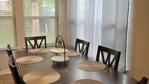 A dining area with a wooden table, six chairs, and three round placemats. - Cozy Home in Spring,TX with AC /WiFi / Laundry . 20 mins from IAH Airport (Spring)