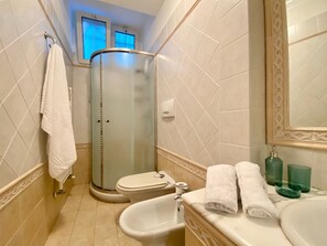 A bathroom with a glass shower enclosure, a toilet, a bidet, and a sink with a mirror. - La Spiaggia (Moneglia)