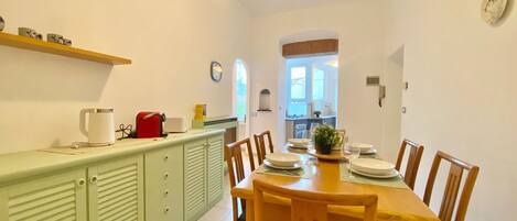 A dining area with a wooden table set for four, flanked by green cabinets and wooden chairs.