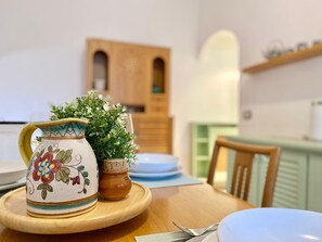 A dining table with a ceramic pitcher, a small potted plant, and a wooden chair. - La Spiaggia (Moneglia)