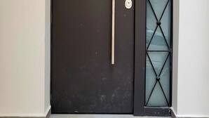 Une porte de couleur sombre, dotée d’une poignée verticale et d’un panneau de verre orné d’un motif en losanges.