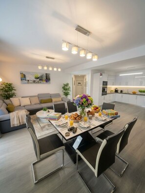 Een moderne woonruimte met een eethoek, een bank, een salontafel en een keuken op de achtergrond.