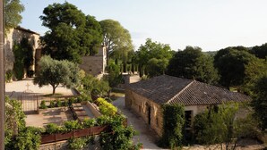 A courtyard with stone buildings, a paved area with seating, and surrounding greenery. - PRIEURÉ SAINT NICOLAS - LES MAISONS (Sainte-Anastasie)