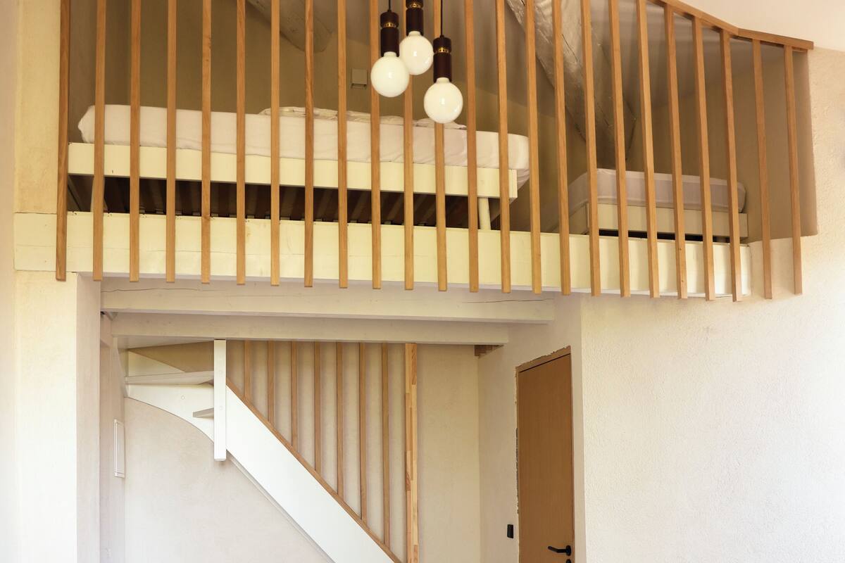 A bedroom with a bunk bed, a wooden staircase, and a bedside table.