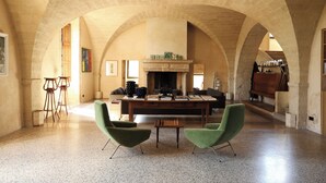 A spacious room with high arched ceilings, a fireplace, and two green armchairs. - PRIEURÉ SAINT NICOLAS - LES MAISONS (Sainte-Anastasie)