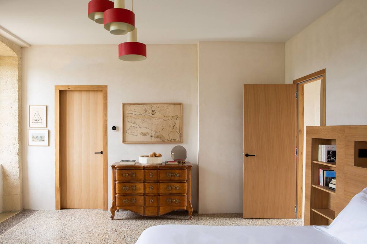 A bedroom with a bed, wooden dresser, map on the wall, and a bookshelf.
