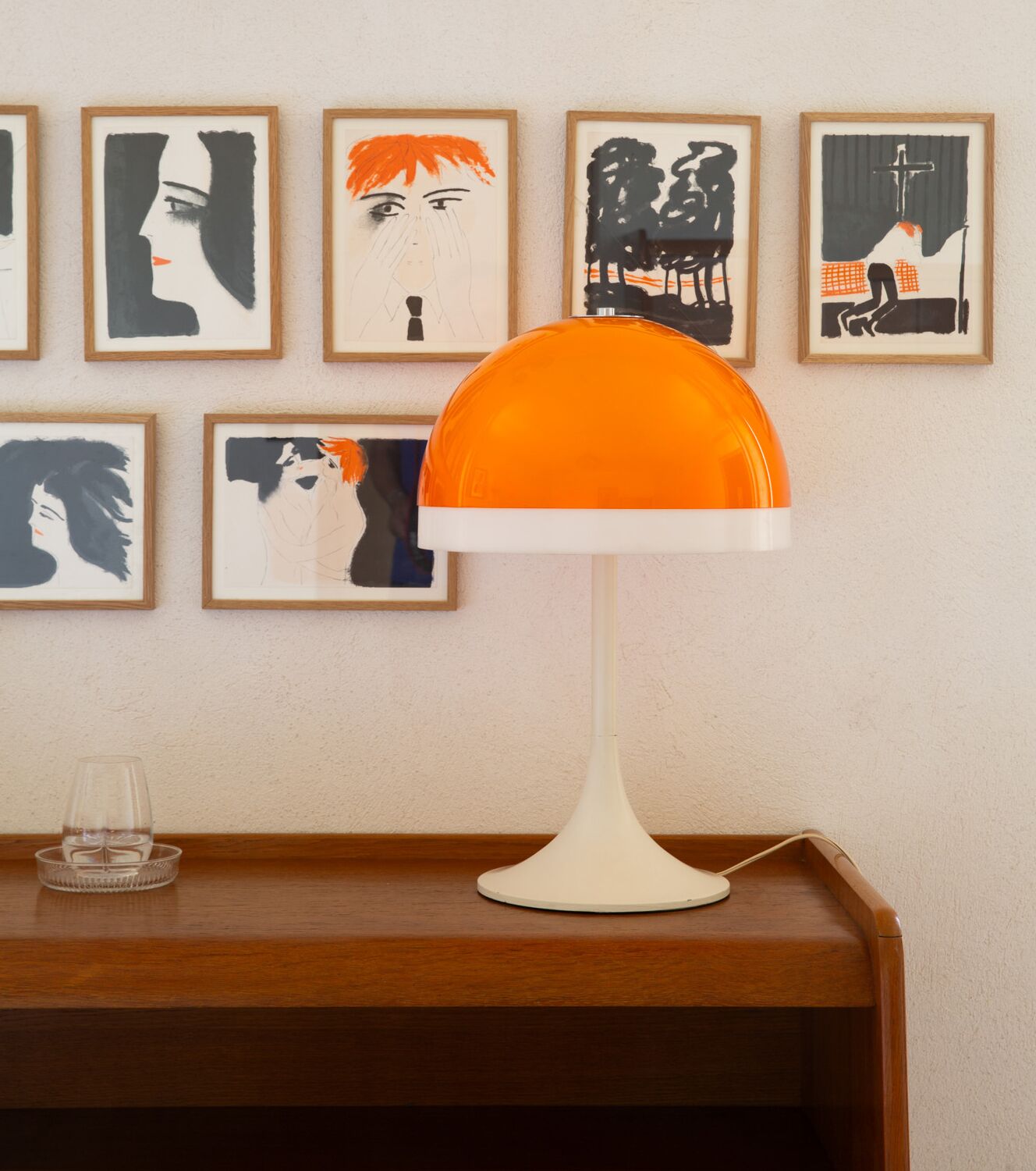A table with a white lamp and a glass of water.