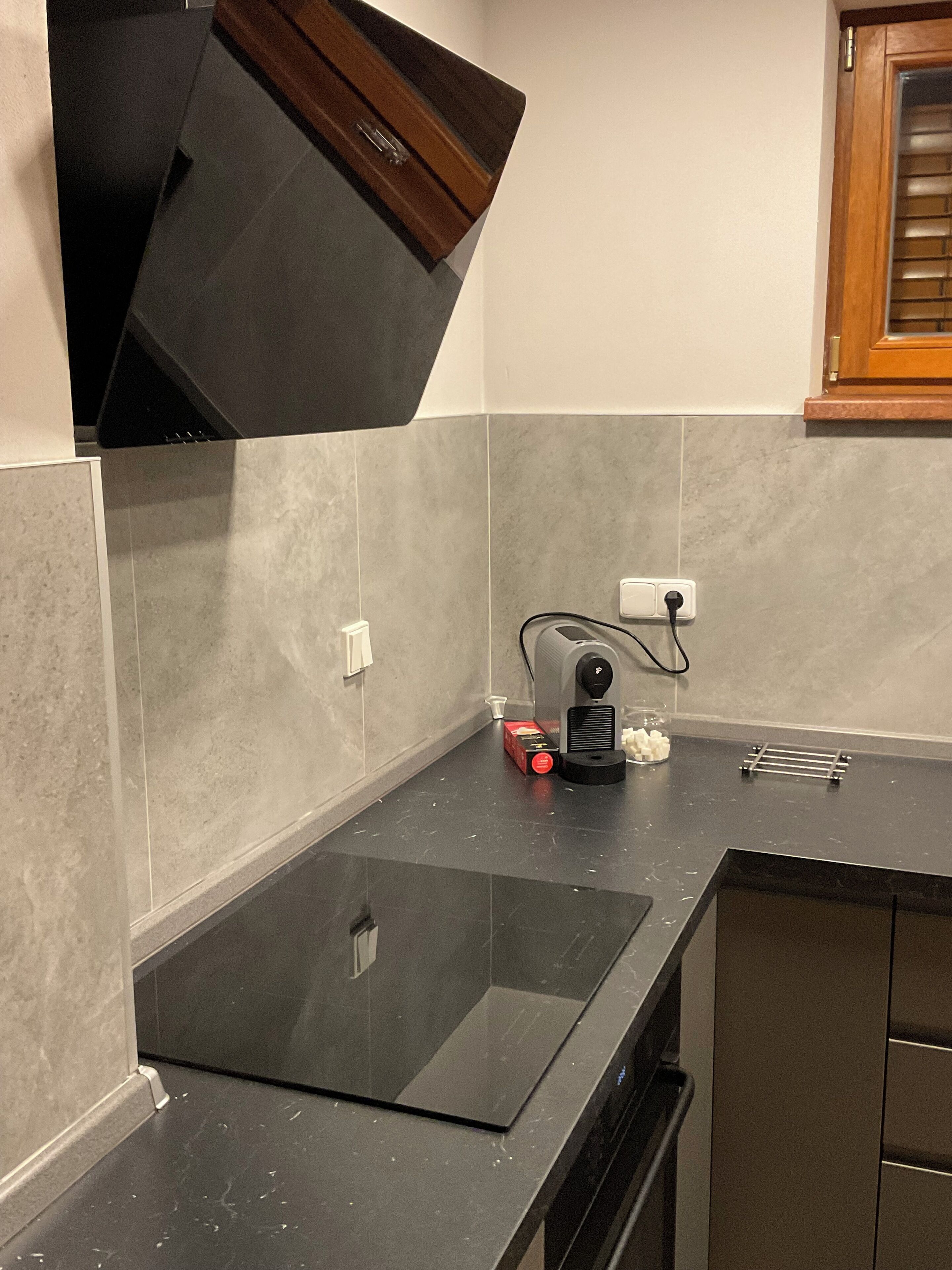 Una cocina moderna con encimera negra, horno integrado y microondas.