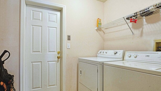 A laundry room with two washers and dryers, a white door, and a shelf with laundry supplies. - Rare Disney-Area Waterfront Retreat | Pool & Fountain Views (Kissimmee)