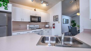 A modern kitchen with white cabinets, stainless steel appliances, and a large island with a sink. - Rare Disney-Area Waterfront Retreat | Pool & Fountain Views (Kissimmee)