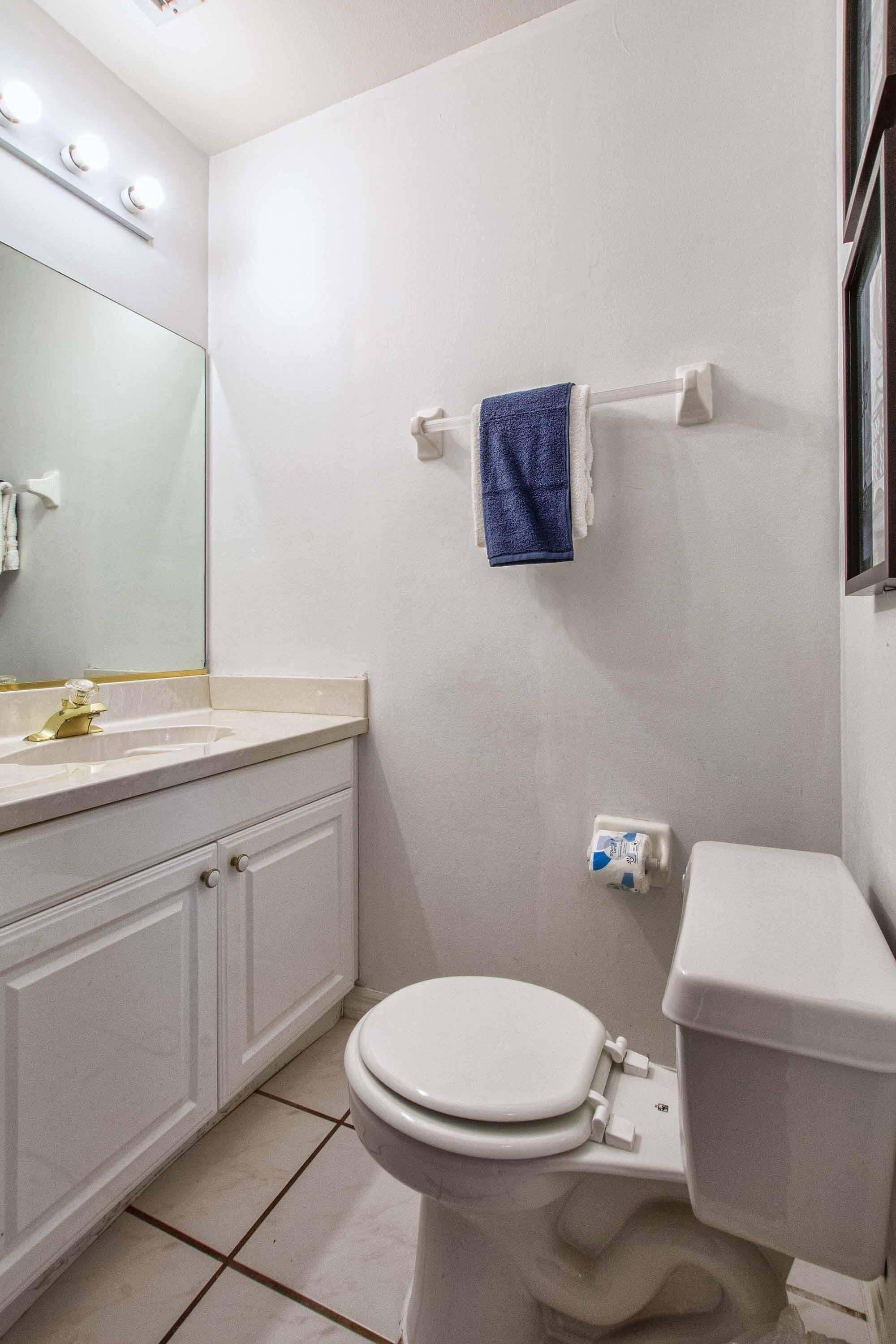 A bathroom with a toilet, sink, mirror, and towel rack.