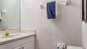 A bathroom with a toilet, sink, mirror, and towel rack. - Rare Disney-Area Waterfront Retreat | Pool & Fountain Views (Kissimmee)